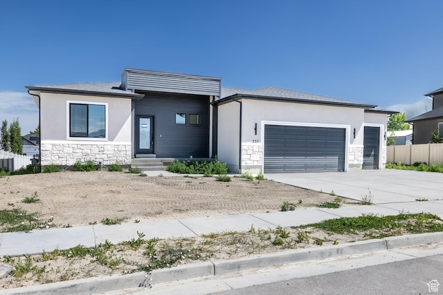 335 E Ventura Blvd, Stansbury Park, UT 84074 - view of front of property with stone siding, an attached garage, driveway, stucco siding, and entry steps