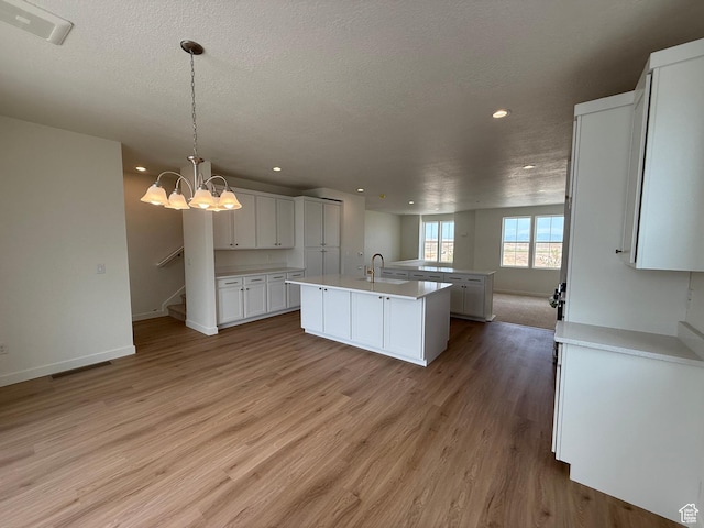 6927 W S Jordan Pkwy, South Jordan, UT 84009 - kitchen with light wood-style floors, light countertops, an island with sink, recessed lighting, and white cabinets