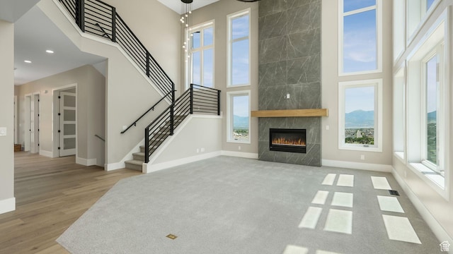 7233 W Summit Top Ln, Herriman, UT 84096 - unfurnished living room with a high ceiling, stairs, a tiled fireplace, wood finished floors, and recessed lighting
