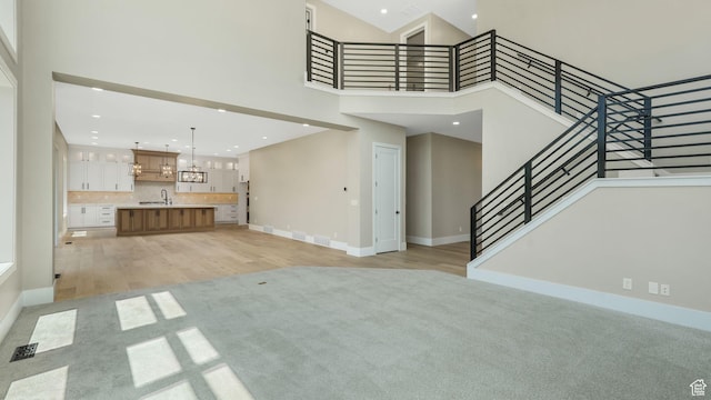 7233 W Summit Top Ln, Herriman, UT 84096 - unfurnished living room featuring a high ceiling, light colored carpet, a chandelier, stairs, and recessed lighting