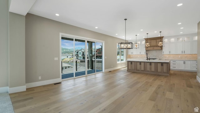 7233 W Summit Top Ln, Herriman, UT 84096 - kitchen featuring a chandelier, light countertops, backsplash, white cabinets, and open floor plan