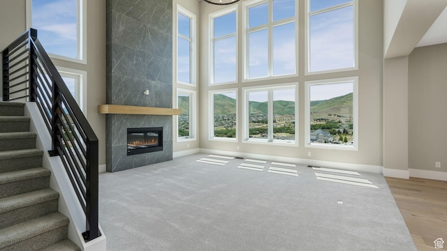 7233 W Summit Top Ln, Herriman, UT 84096 - unfurnished living room featuring a towering ceiling, a mountain view, a fireplace, and stairway