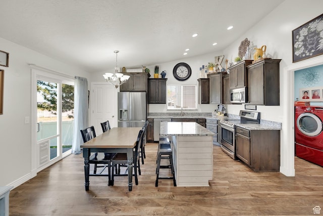 369 E Shelley Ln, Grantsville, UT 84029 - kitchen with stainless steel appliances, washer / clothes dryer, dark brown cabinets, a chandelier, and light wood-style floors