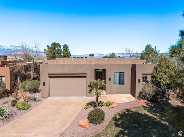 4962 W Boulder Vw, Hurricane, UT 84737 - pueblo-style house with an attached garage, concrete driveway, stucco siding, and a mountain view