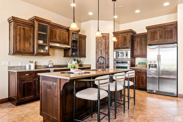 4962 W Boulder Vw, Hurricane, UT 84737 - kitchen with stainless steel appliances, an island with sink, a kitchen bar, light tile patterned floors, and dark brown cabinetry