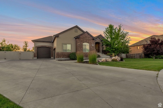 4948 W 4025 S, West Haven, UT 84401 - mediterranean / spanish-style house featuring concrete driveway, an attached garage, stucco siding, a gate, and brick siding