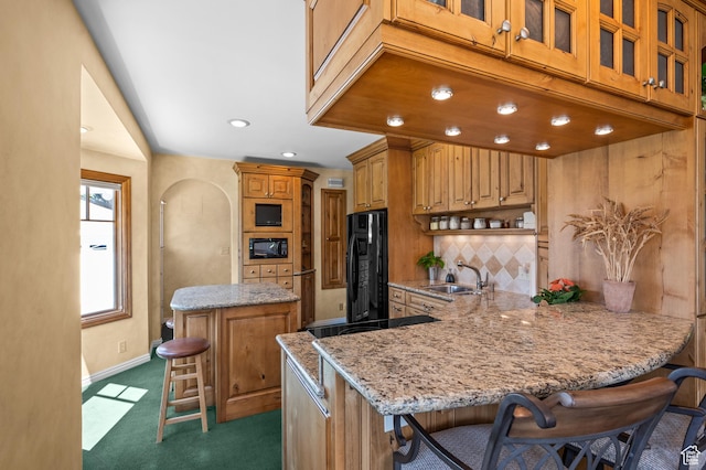 1632 S 1500 E, Salt Lake City, UT 84105 - kitchen featuring black appliances, decorative backsplash, light stone counters, a kitchen breakfast bar, and a peninsula