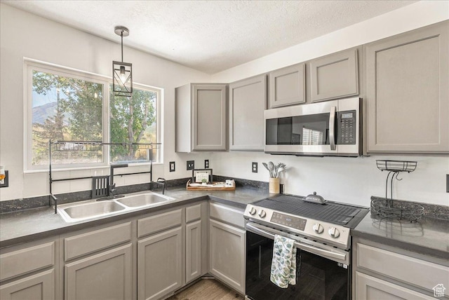 655 S 100 W, Santaquin, UT 84655 - kitchen featuring appliances with stainless steel finishes, gray cabinetry, dark countertops, a textured ceiling, and hanging light fixtures