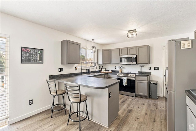 655 S 100 W, Santaquin, UT 84655 - kitchen with stainless steel appliances, a peninsula, gray cabinetry, dark countertops, and a kitchen bar