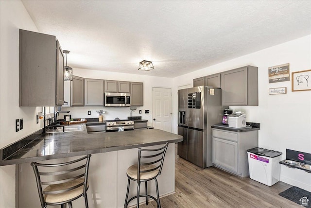 655 S 100 W, Santaquin, UT 84655 - kitchen with stainless steel appliances, dark countertops, a peninsula, gray cabinets, and a textured ceiling
