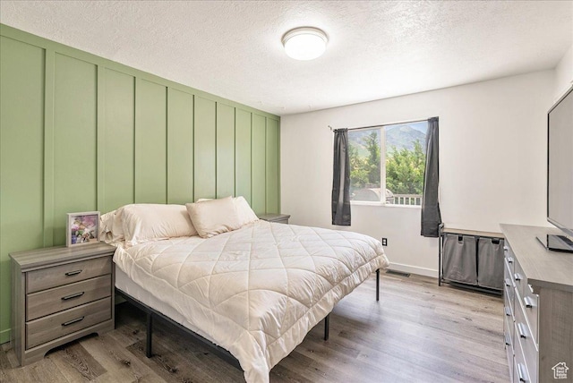 655 S 100 W, Santaquin, UT 84655 - bedroom featuring light wood-style floors, a textured ceiling, and a decorative wall