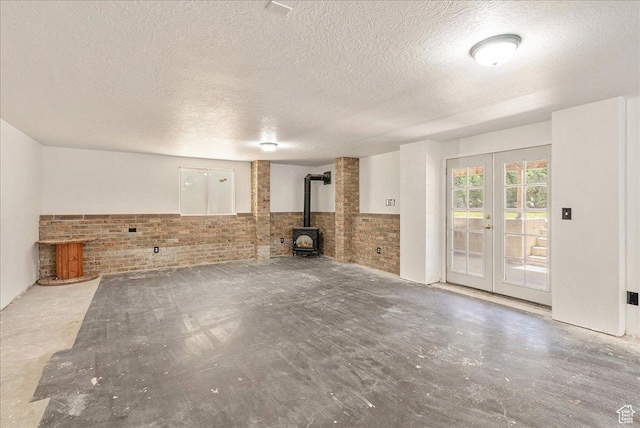 655 S 100 W, Santaquin, UT 84655 - unfurnished living room featuring a wood stove, brick wall, french doors, a textured ceiling, and concrete floors