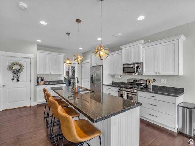 4966 W Willamette Way S, South Jordan, UT 84095 - kitchen with stainless steel appliances, stacked washer / drying machine, dark wood-type flooring, decorative backsplash, and white cabinetry