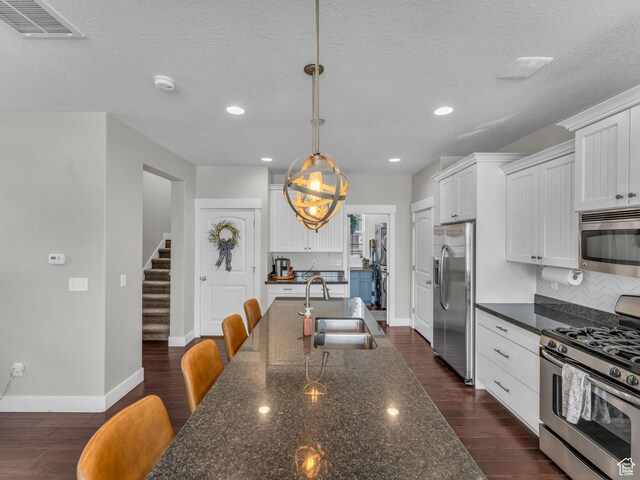 4966 W Willamette Way S, South Jordan, UT 84095 - kitchen with appliances with stainless steel finishes, white cabinetry, dark wood-type flooring, tasteful backsplash, and recessed lighting