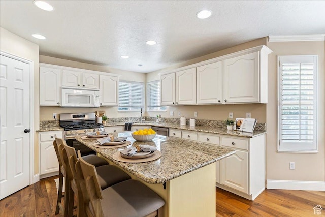 677 E 2900 N, North Ogden, UT 84414 - kitchen with stainless steel appliances, a breakfast bar area, white cabinets, crown molding, and wood finished floors