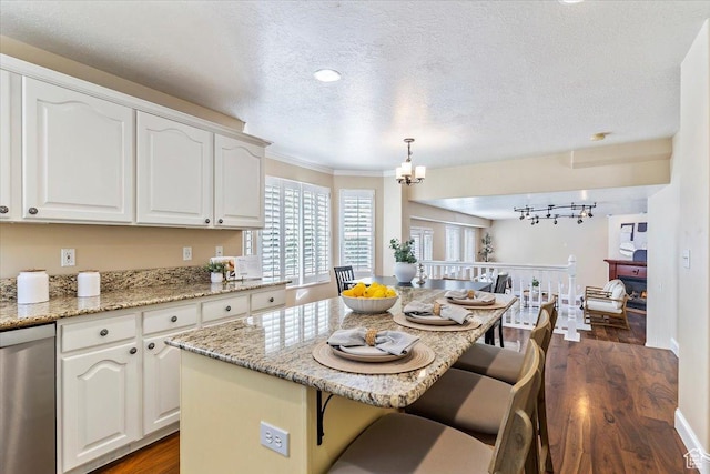 677 E 2900 N, North Ogden, UT 84414 - kitchen with stainless steel dishwasher, dark wood-style flooring, a kitchen breakfast bar, a chandelier, and white cabinets