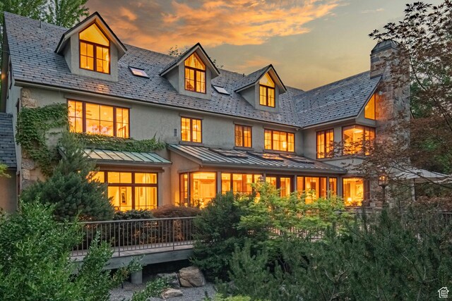 6033 S 2300 E, Holladay, UT 84121 - back of house at dusk featuring a standing seam roof, a high end roof, a metal roof, stucco siding, and a chimney