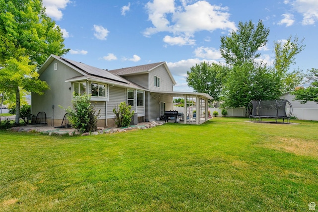 13082 S 2770th Cir W, Riverton, UT 84065 - back of property featuring a trampoline, a patio, solar panels, and a fenced backyard