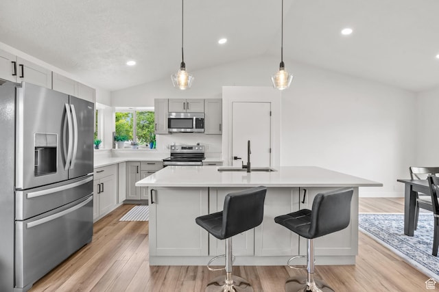 13082 S 2770th Cir W, Riverton, UT 84065 - kitchen with appliances with stainless steel finishes, vaulted ceiling, light countertops, light wood finished floors, and a breakfast bar area