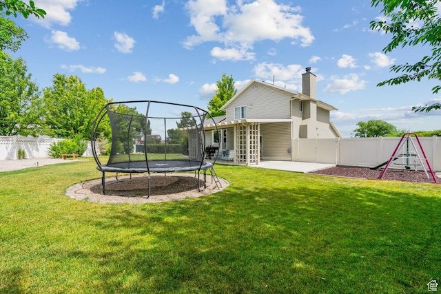 13082 S 2770th Cir W, Riverton, UT 84065 - back of house featuring a trampoline, a chimney, a patio area, a playground, and a fenced backyard