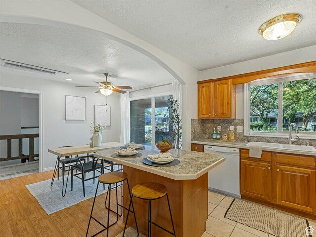 1411 E 1220 N, Logan, UT 84341 - kitchen featuring dishwasher, a textured ceiling, light countertops, decorative backsplash, and a center island