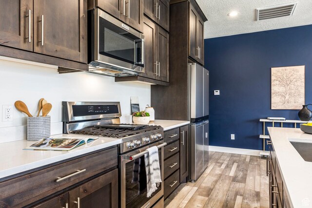 3249 Quarry Springs Dr, Park City, UT 84098 - kitchen featuring appliances with stainless steel finishes, dark brown cabinets, light wood-style floors, light countertops, and a textured ceiling