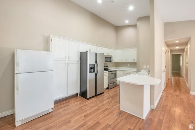 861 W Columbia Ln Unit 21, Provo, UT 84604 - kitchen featuring appliances with stainless steel finishes, a towering ceiling, a peninsula, white cabinetry, and light wood-style flooring