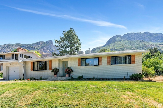 2040 N Oakcrest Ter, Provo, UT 84604 - view of front facade featuring a mountain view, brick siding, a chimney, a front yard, and an attached garage
