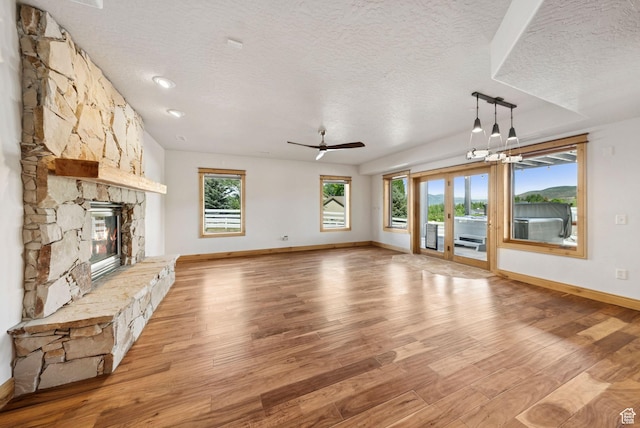 4555 Palomino Dr, Heber City, UT 84032 - unfurnished living room with a textured ceiling, a fireplace, light wood-style floors, and ceiling fan
