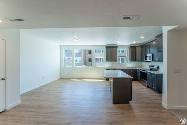 8333 S Iris Lumi Ln W Unit Q304, Midvale, UT 84047 - kitchen with stainless steel appliances, a center island, light countertops, light wood finished floors, and open floor plan