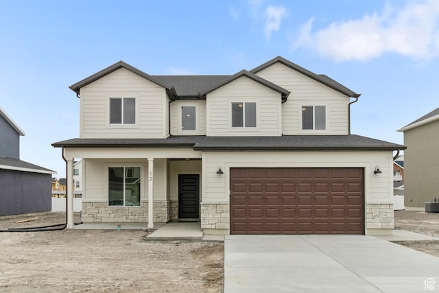 167 N 950 E Unit 30, Tremonton, UT 84337 - view of front of property featuring covered porch, a garage, stone siding, driveway, and roof with shingles