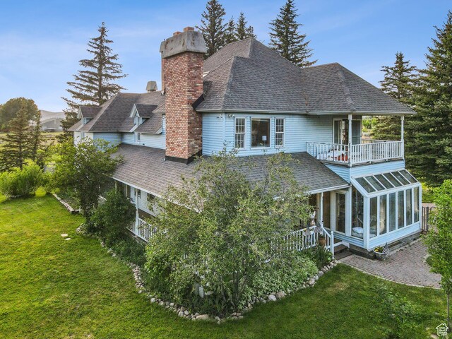 455 E Boulderville Rd, Oakley, UT 84055 - back of house featuring a chimney, a sunroom, a balcony, a shingled roof, and a yard