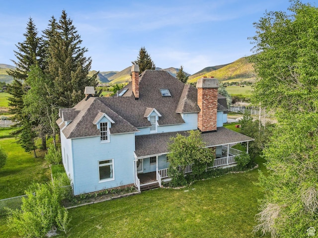 455 E Boulderville Rd, Oakley, UT 84055 - back of house with a chimney, a lawn, a porch, a shingled roof, and a mountain view