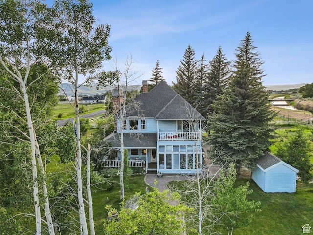 455 E Boulderville Rd, Oakley, UT 84055 - back of house featuring a balcony, a chimney, a shingled roof, a lawn, and an outbuilding