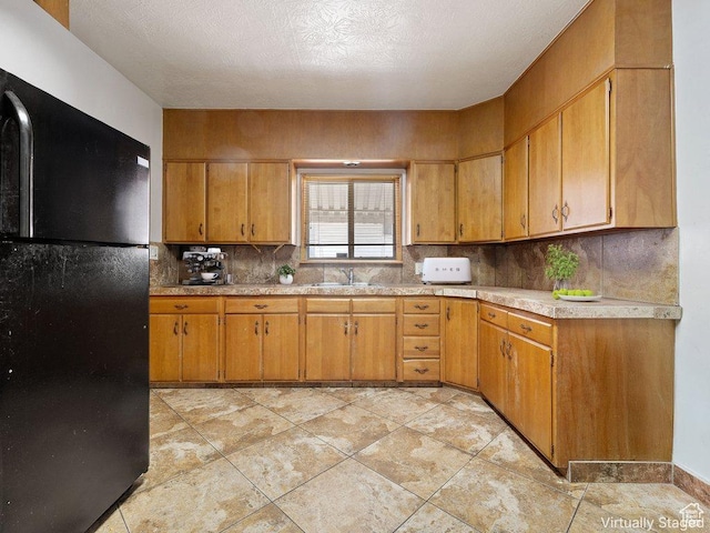 792 W 100 N, Provo, UT 84601 - kitchen featuring freestanding refrigerator, light countertops, decorative backsplash, brown cabinetry, and a textured ceiling