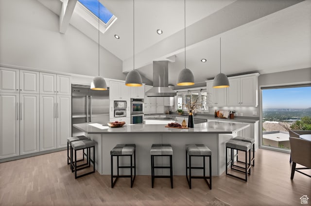 4504 S Abinadi Rd E, Millcreek, UT 84124 - kitchen featuring island exhaust hood, a skylight, stainless steel appliances, high vaulted ceiling, and white cabinetry