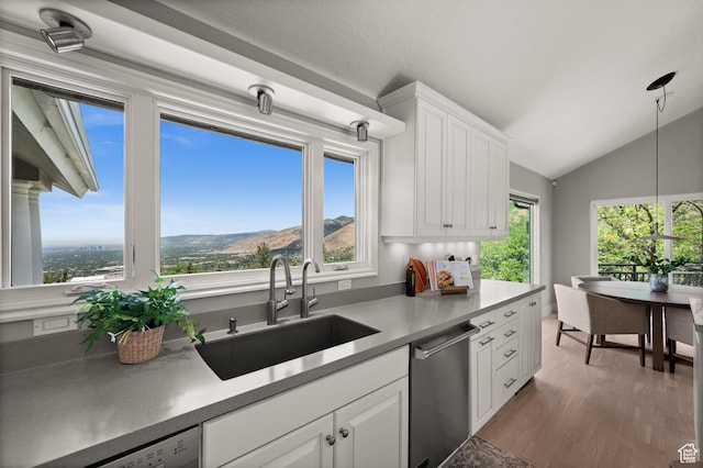 4504 S Abinadi Rd E, Millcreek, UT 84124 - kitchen with stainless steel dishwasher, vaulted ceiling, white cabinets, pendant lighting, and wood finished floors