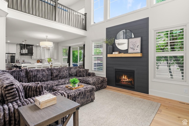 855 E Snap Dragon Ln, Fruit Heights, UT 84037 - living area featuring a high ceiling, healthy amount of natural light, light wood-style floors, and a glass covered fireplace