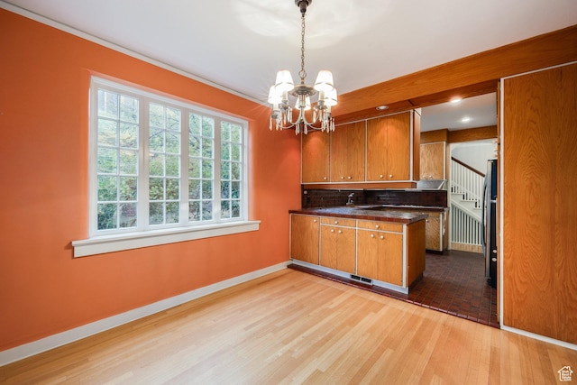 116 S University St E, Salt Lake City, UT 84102 - kitchen featuring brown cabinetry, dark countertops, a chandelier, and a peninsula