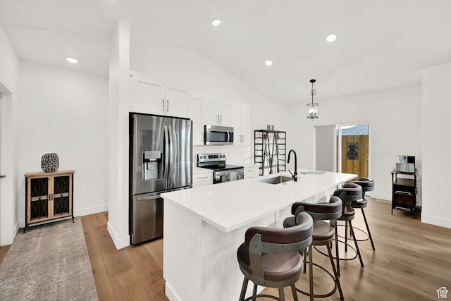 88 N Maraschino W, Grantsville, UT 84029 - kitchen with stainless steel appliances, light wood-style floors, a center island with sink, white cabinets, and vaulted ceiling