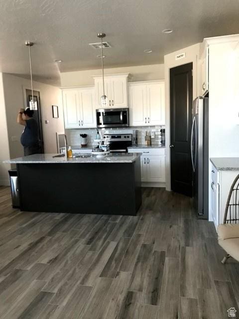 4895 N Fishers Island Way, St George, UT 84770 - kitchen featuring stainless steel appliances, white cabinets, a kitchen island with sink, dark wood-type flooring, and hanging light fixtures
