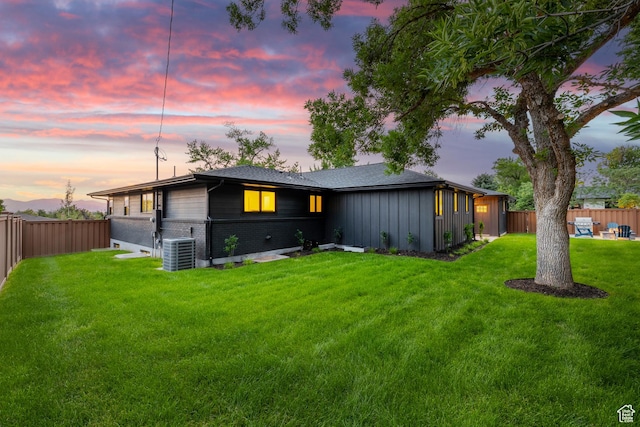 5223 S Hillsden Dr, Holladay, UT 84117 - back of property at dusk featuring brick siding, a fenced backyard, and board and batten siding