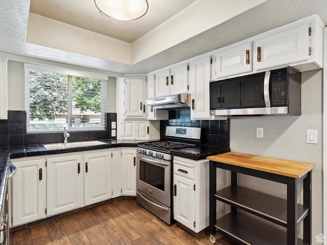2203 N Joni Dr E, Layton, UT 84040 - kitchen featuring appliances with stainless steel finishes, under cabinet range hood, white cabinets, dark wood finished floors, and backsplash