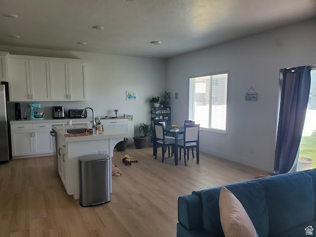 1082 E Springwater Way Unit 812, Eagle Mountain, UT 84005 - kitchen featuring light wood finished floors, white cabinetry, light countertops, open floor plan, and freestanding refrigerator