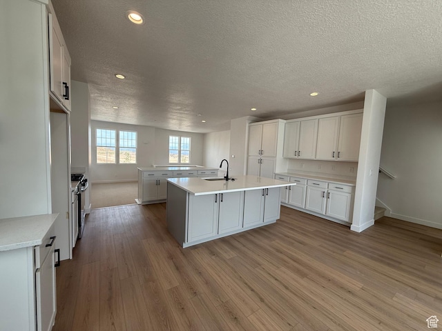 6923 W S Jordan Pkwy S, South Jordan, UT 84009 - kitchen with a textured ceiling, wood finished floors, a kitchen island with sink, light countertops, and recessed lighting
