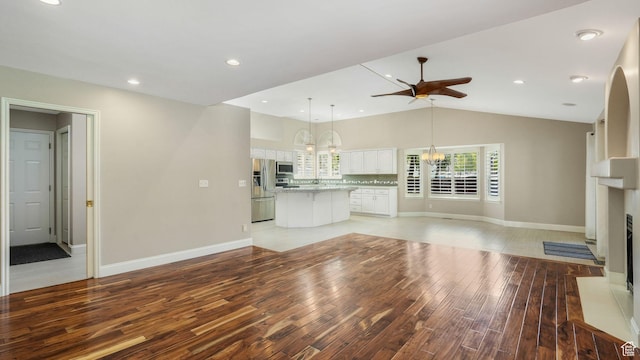 6320 S Hathaway St, Taylorsville, UT 84123 - unfurnished living room featuring light wood-style flooring, a ceiling fan, a fireplace, a chandelier, and lofted ceiling
