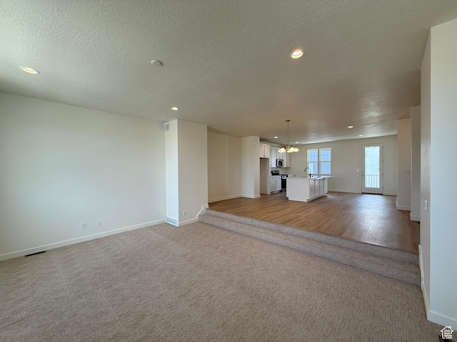 6921 W S Jordan Pkwy Unit 310, South Jordan, UT 84009 - unfurnished living room featuring a chandelier, light carpet, recessed lighting, and a textured ceiling