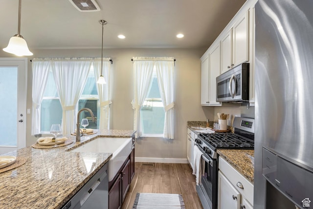 10572 S Kestrel Rise Rd, South Jordan, UT 84009 - kitchen featuring stainless steel appliances, wood finished floors, white cabinetry, pendant lighting, and light stone counters
