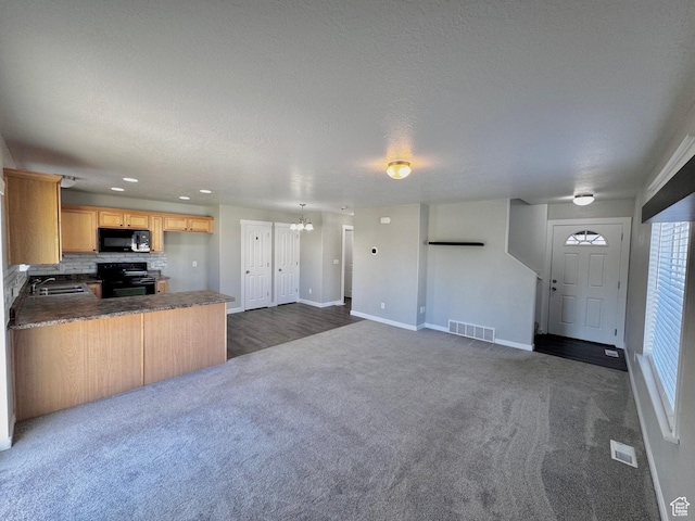 2061 Revere Way, Eagle Mountain, UT 84005 - kitchen with black appliances, dark colored carpet, a peninsula, a chandelier, and backsplash