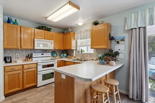 801 W Harrisville Rd N Unit 14, Ogden, UT 84404 - kitchen with white appliances, a kitchen bar, a peninsula, light wood finished floors, and backsplash